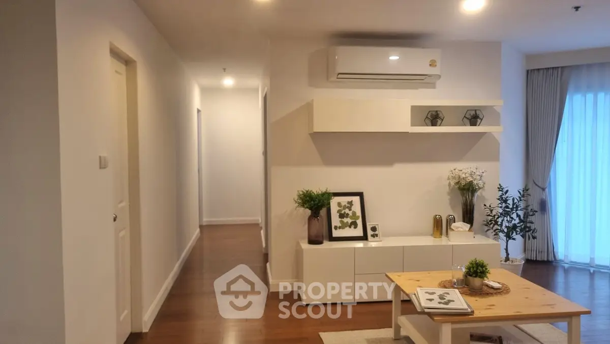 Modern living room with stylish decor and air conditioning, featuring wooden flooring and natural light.