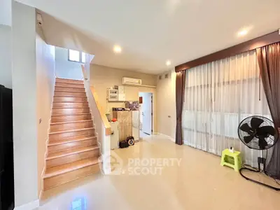 Spacious living room with staircase and large window, perfect for family gatherings.