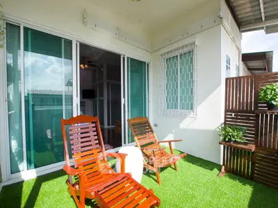 Charming balcony with wooden chairs and lush artificial grass, perfect for relaxation.