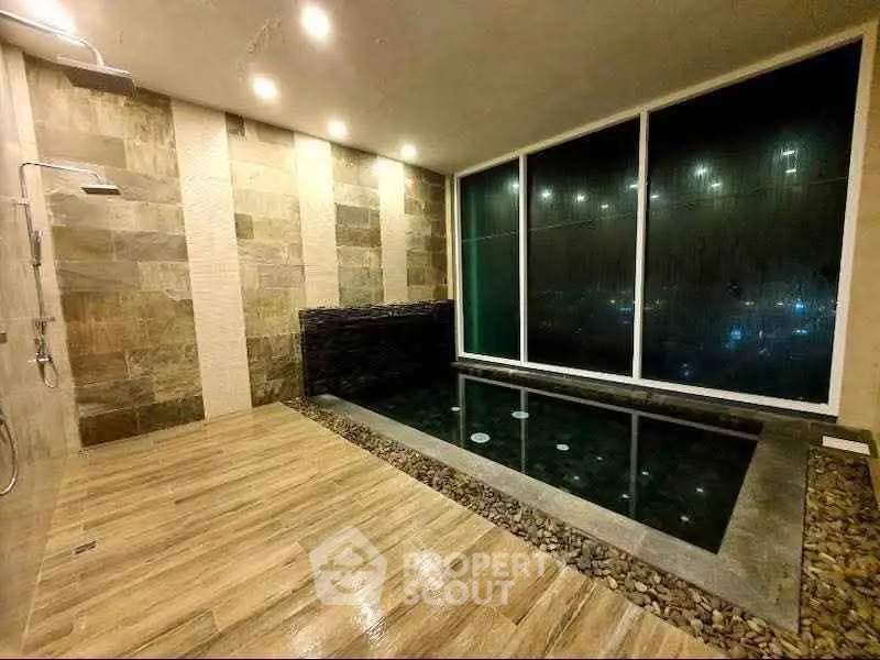 Luxurious indoor pool with modern stone and wood finishes, perfect for relaxation and entertainment.