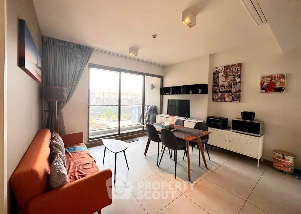 Modern living room with dining area and large windows offering natural light.
