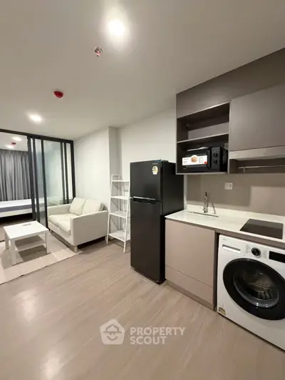 Modern apartment with open kitchen, washing machine, and cozy living area.
