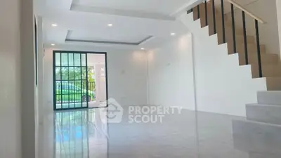 Spacious modern living room with staircase and large windows for natural light.