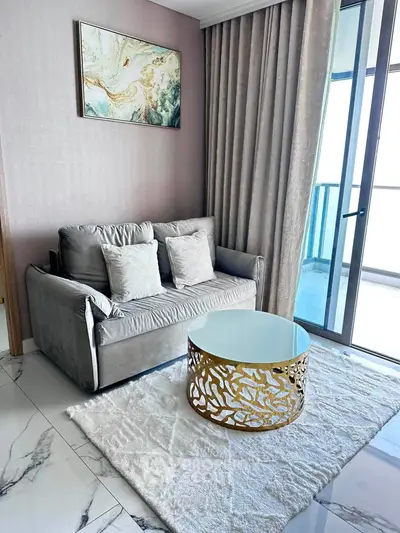 Elegant living room with plush sofa, artistic coffee table, and balcony view in modern apartment.