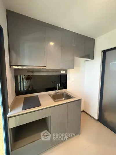 Modern compact kitchen with sleek grey cabinets and built-in sink