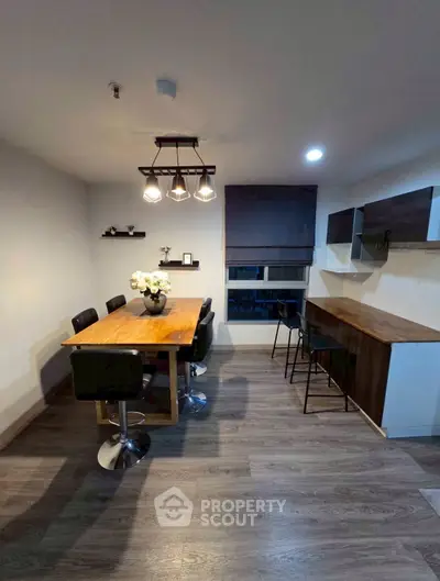 Modern dining area with stylish lighting and wooden furniture in open layout.