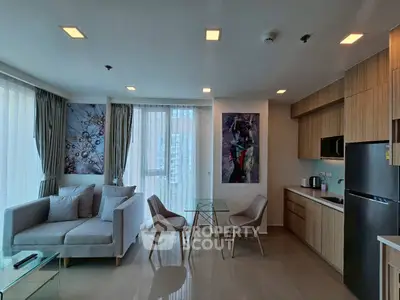 Modern open-layout living room with kitchen, featuring stylish decor and natural light.