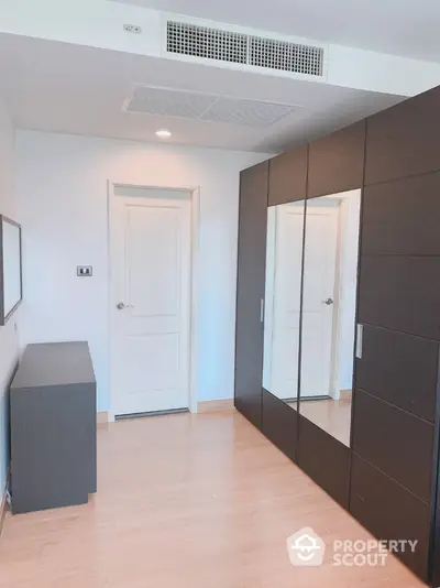 Spacious bedroom with mirrored wardrobe and modern decor