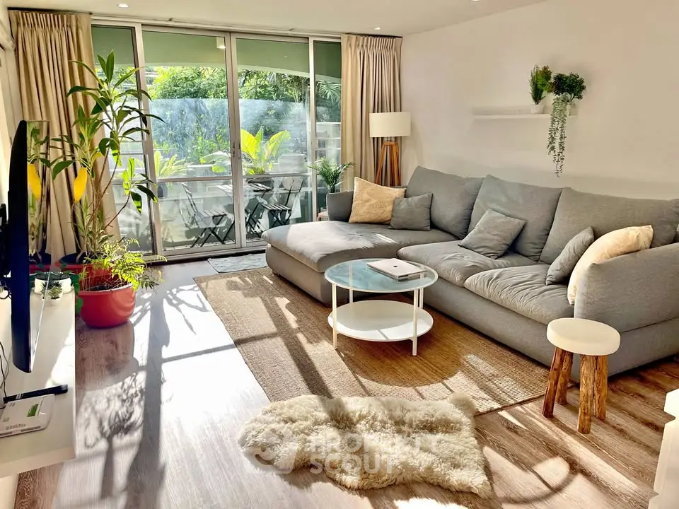 Bright and cozy living room with large windows and lush balcony view.