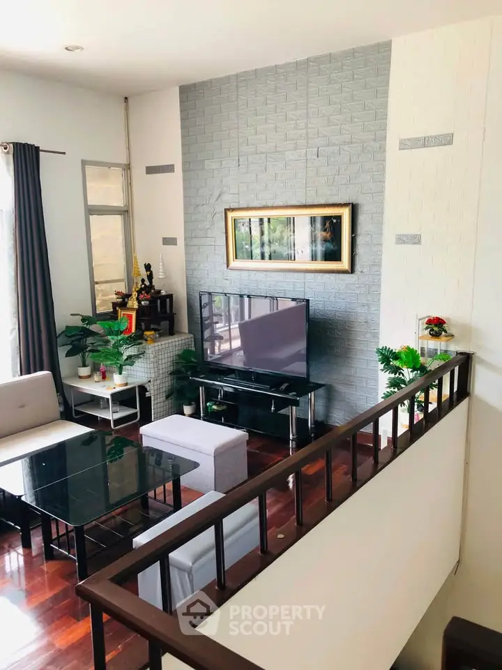 Stylish living room with modern decor and large TV, featuring elegant furniture and natural light.