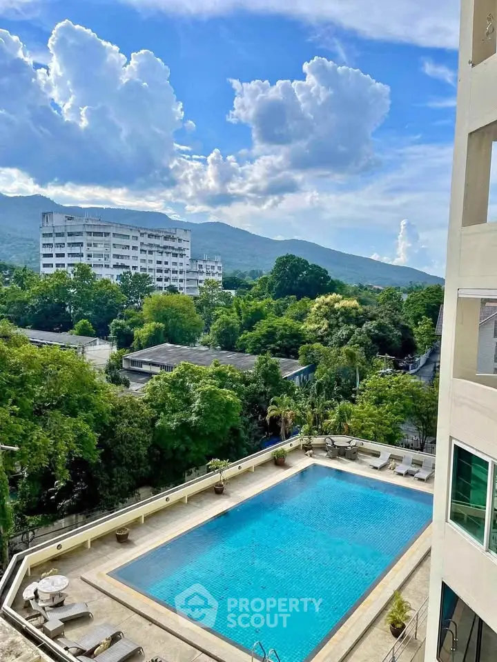 Stunning pool view with lush greenery and mountain backdrop in a modern residential complex.