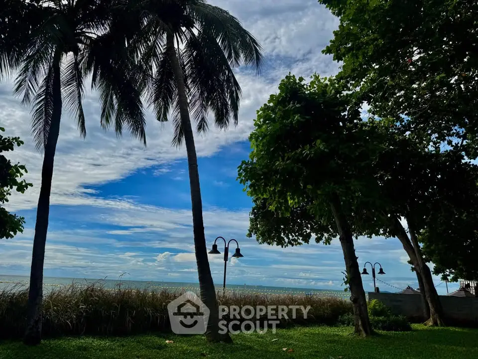 Stunning beachfront view with lush greenery and palm trees under a vibrant sky.