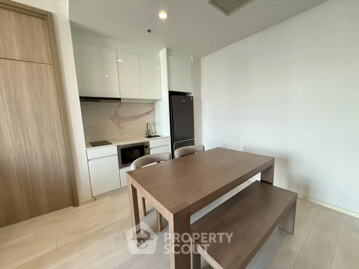 Modern kitchen with dining table and sleek appliances in a minimalist design.