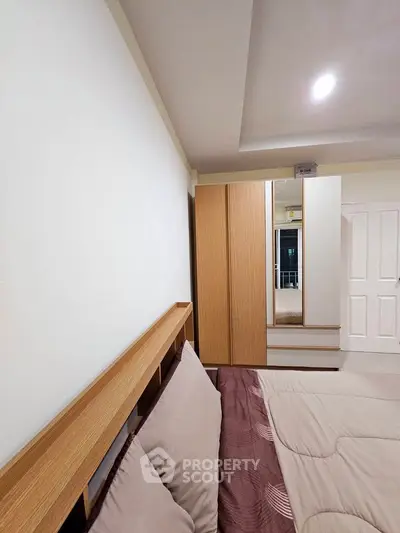 Modern bedroom with stylish wooden headboard and sleek wardrobe design.