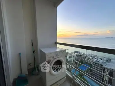 Stunning balcony view with washing machine overlooking ocean and cityscape at sunset.