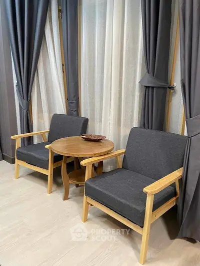 Cozy seating area with modern chairs and table by large windows, perfect for relaxation.