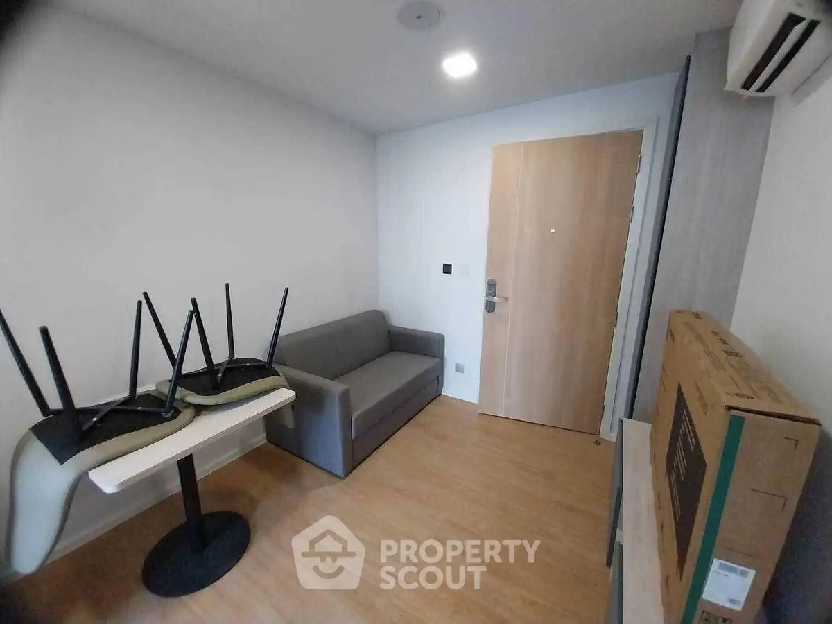 Compact living room with sofa, table, and boxed TV in modern apartment.