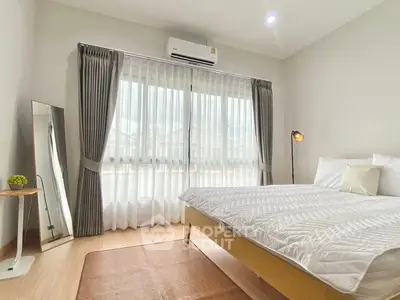 Bright and cozy bedroom with modern decor and large window.