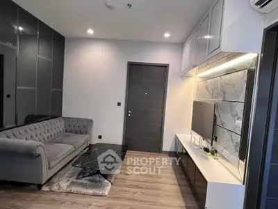 Modern living room with sleek design, featuring a stylish grey sofa and marble accents.