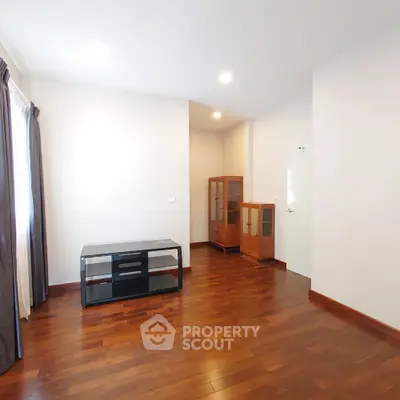 Spacious and well-lit living room with polished hardwood flooring and minimalist decor, ready for personalization.