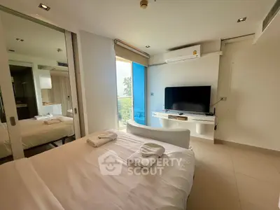 Modern bedroom with balcony view and sleek TV setup in a stylish apartment.