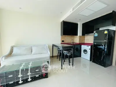 Modern apartment with sleek kitchen and cozy living area, featuring washing machine and fridge.