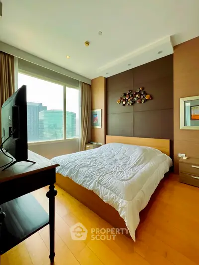 Spacious bedroom with modern decor and large window offering city views.