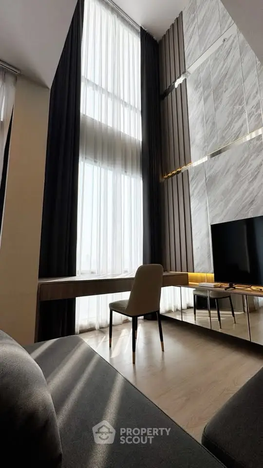 Luxurious high-ceiling living room with elegant decor and floor-to-ceiling windows.