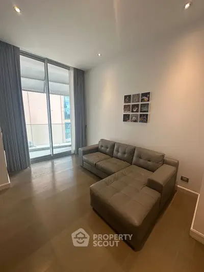 Modern living room with sleek sofa and floor-to-ceiling windows leading to balcony.