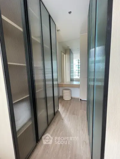 Spacious walk-in closet with modern glass doors and elegant wooden flooring