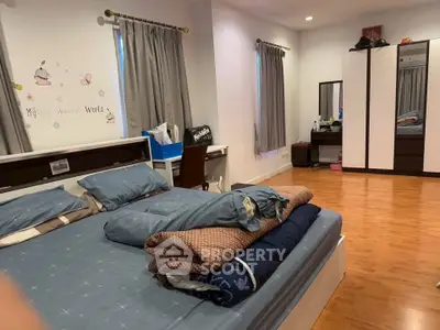 Spacious bedroom with wooden flooring and modern furniture