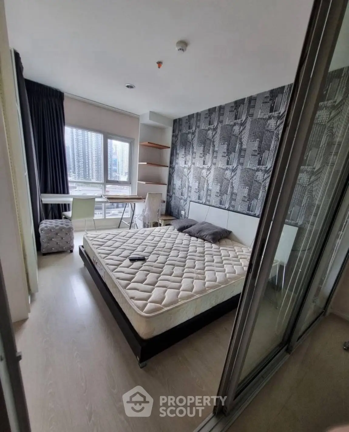 Modern bedroom with city view, stylish wallpaper, and cozy furnishings.