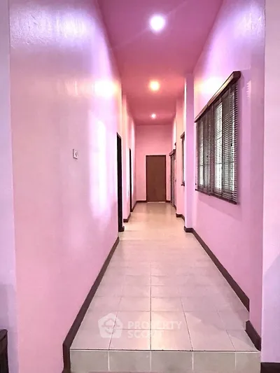 Spacious pink hallway with tiled flooring and modern lighting.