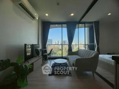 Modern living room with city view, featuring sleek furniture and large windows.