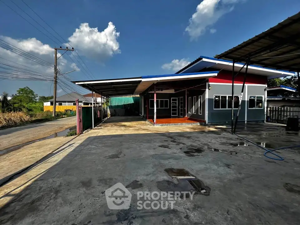 Spacious modern house with large driveway and covered parking area under clear blue sky.