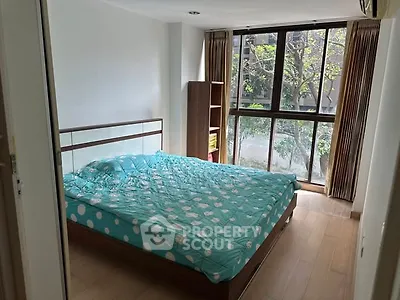 Spacious bedroom with large window and modern decor in a serene setting.