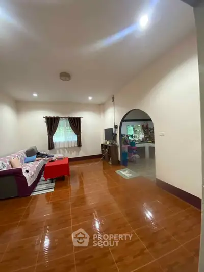 Spacious living room with cozy sofa and open layout leading to kitchen area.