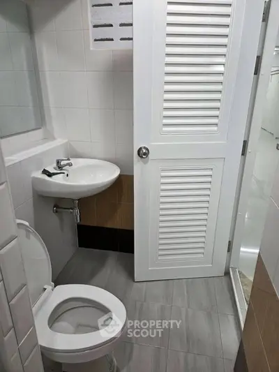 Compact bathroom with modern fixtures and sleek design, featuring a white sink and toilet.
