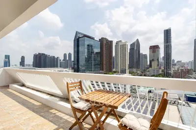 Stunning cityscape view from a spacious balcony with modern outdoor seating, perfect for relaxation.