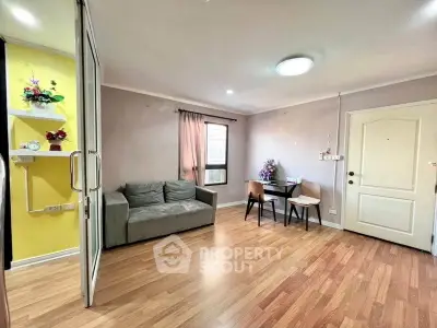 Cozy living room with wooden flooring, sofa, and dining area in modern apartment.