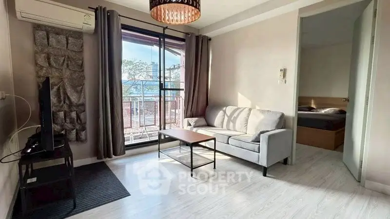 Modern living room with balcony and natural light, featuring a cozy sofa and stylish decor.