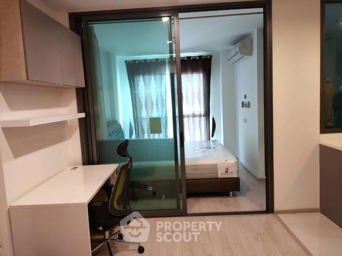 Modern apartment with study area and bedroom separated by glass sliding door