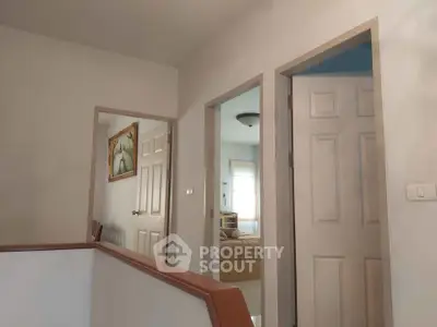Spacious hallway with open doors leading to a cozy bedroom, showcasing modern interior design.