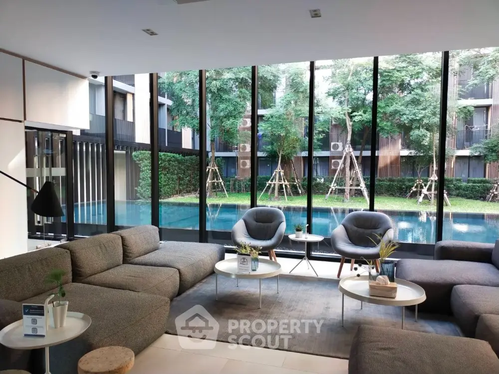 Luxurious living room with floor-to-ceiling windows overlooking a serene pool and landscaped garden, featuring plush seating and modern decor.