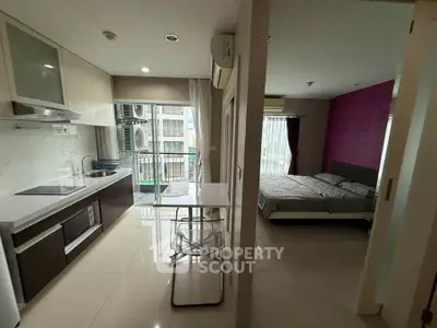 Modern apartment interior with sleek kitchen and cozy bedroom, featuring open layout and natural light.