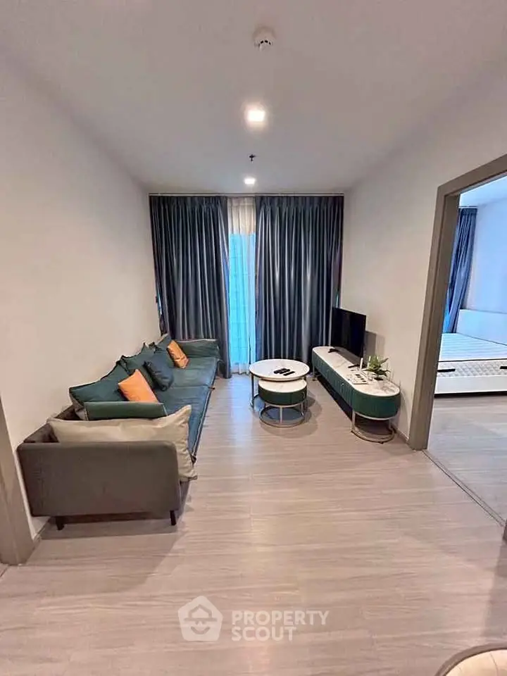 Modern living room with stylish sofa and TV unit, adjacent to a cozy bedroom.