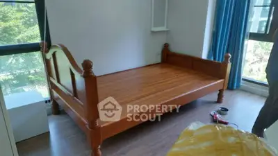 Spacious bedroom with wooden bed and large windows offering natural light.