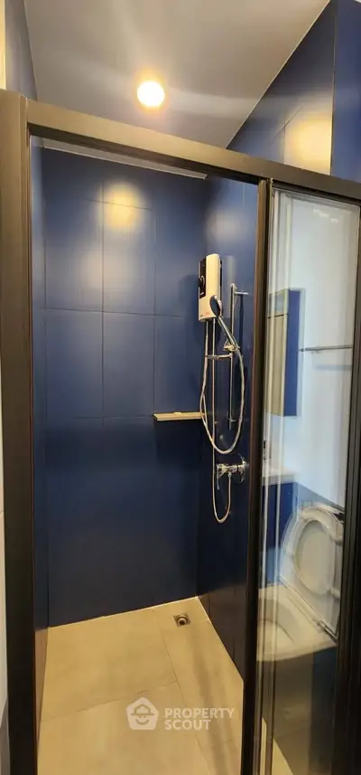 Modern bathroom with sleek blue tiles and glass shower enclosure