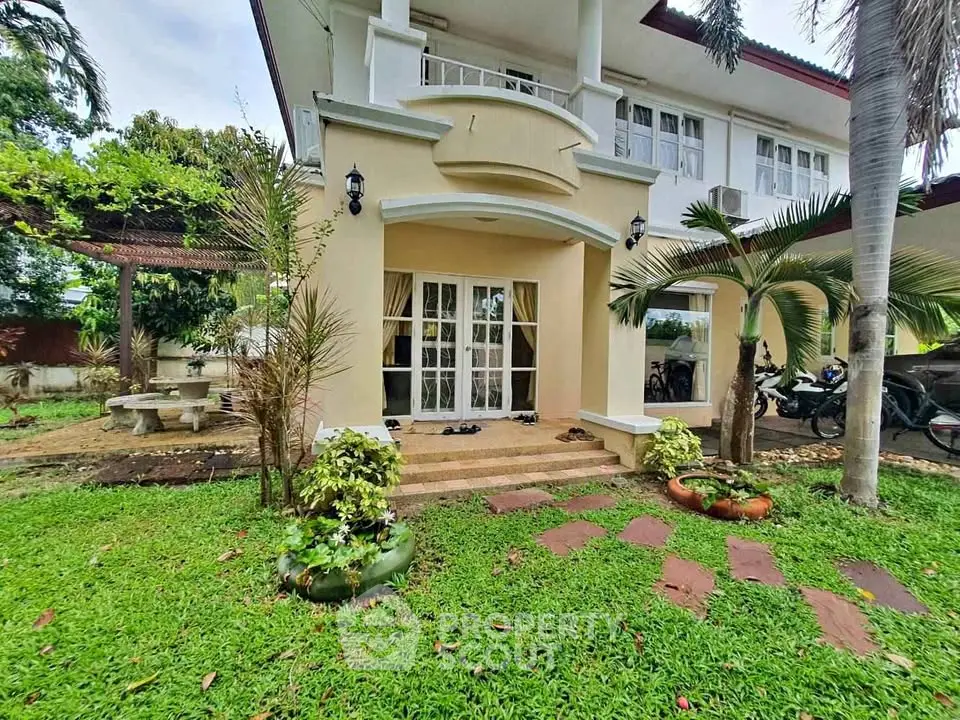 Charming two-story home with lush garden and inviting entrance, perfect for family living.
