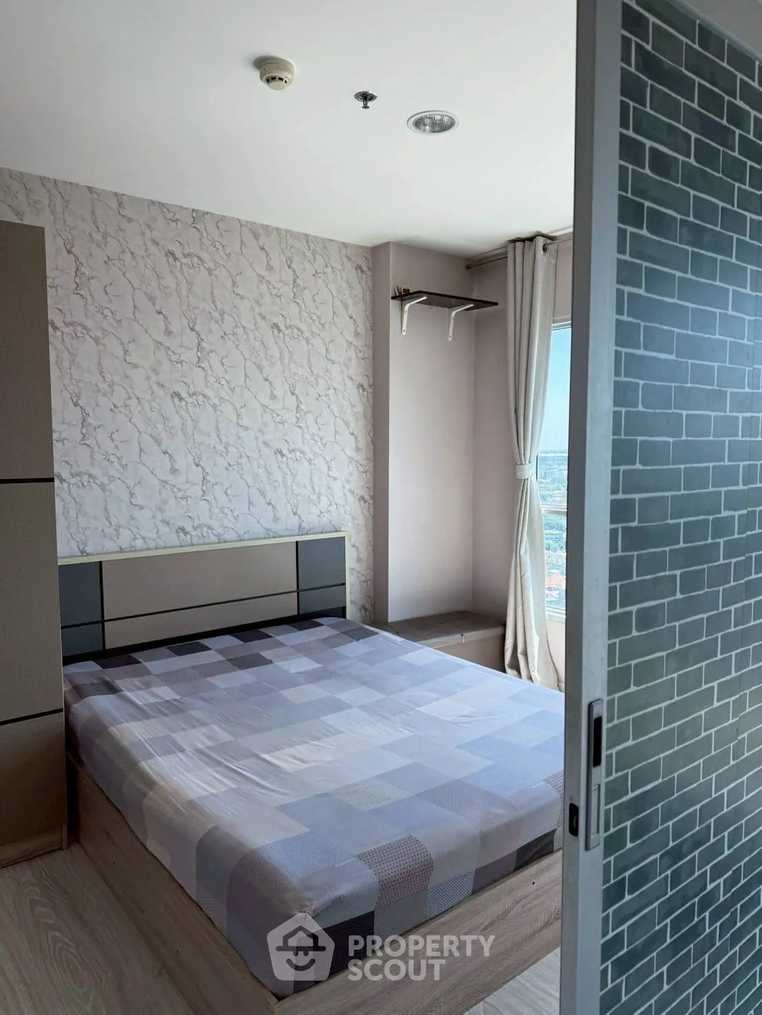 Modern bedroom with stylish decor and large window offering city views.